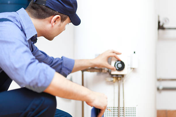 Smiling technician repairing a hot-water heater.